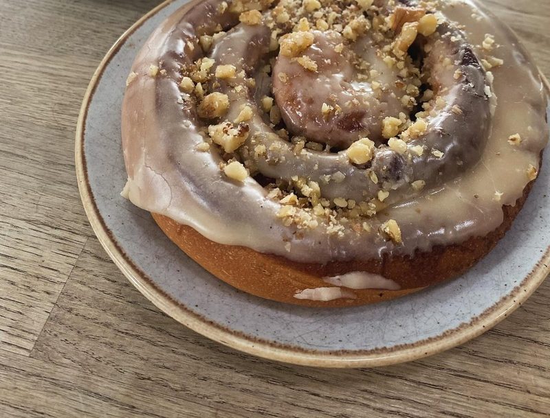Iced cinnamon bun topped with chopped nuts.